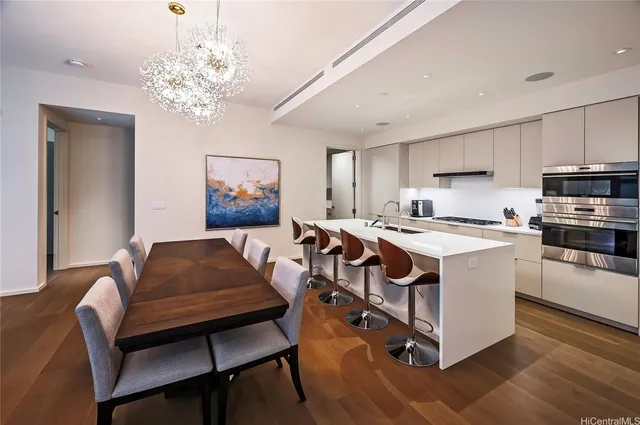 a living room with stainless steel appliances kitchen island granite countertop furniture and a chandelier