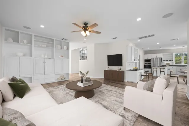 a living room with furniture a flat screen tv and a floor to ceiling window