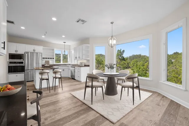 a large white kitchen with wooden floor and stainless steel appliances