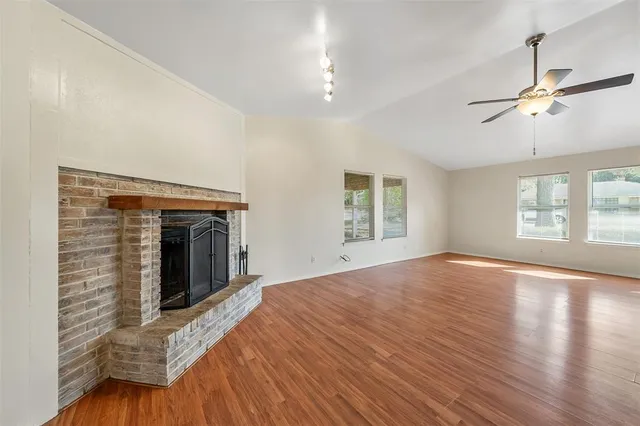 a view of empty room with wooden floor and fan