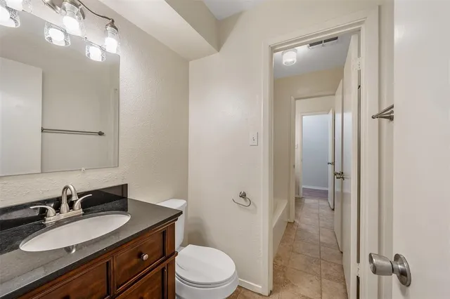 a bathroom with a granite countertop sink toilet a mirror a vanity and shower