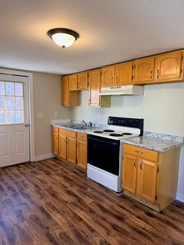 a kitchen with granite countertop a stove a sink and a microwave