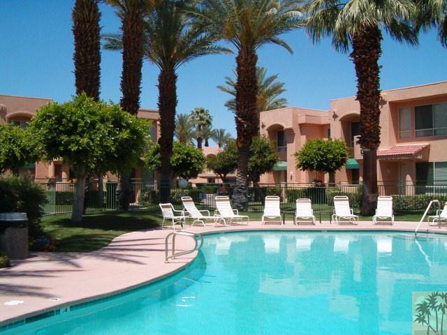 401 El Cielo Road, Unit 29 Palm Springs, CA 92262 - Photo 20 of 25 a view of a swimming pool with a lawn chairs and palm trees