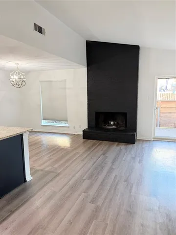 an empty room with wooden floor fire place and windows