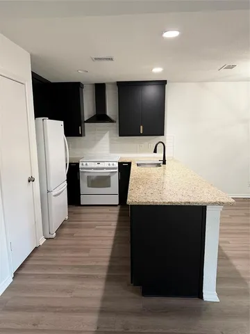 a kitchen with stainless steel appliances kitchen island granite countertop a refrigerator and a sink