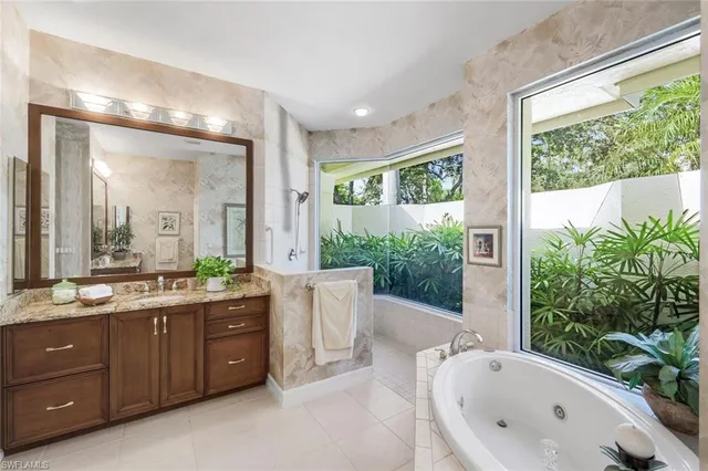 a bathroom with a granite countertop tub sink and mirror