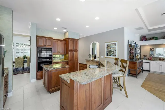 a kitchen with granite countertop a refrigerator a stove a sink a dining table and chairs