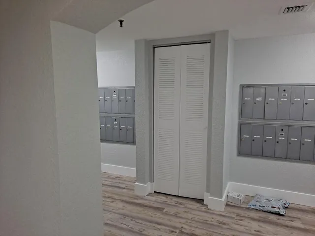 a view of a hallway with wooden floor and cabinet