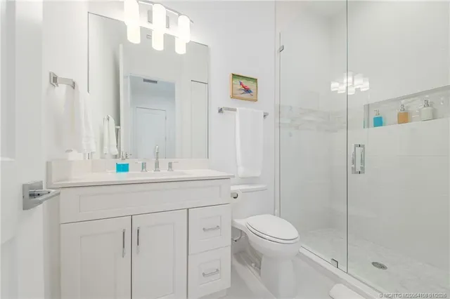 a bathroom with a shower sink vanity mirror and toilet
