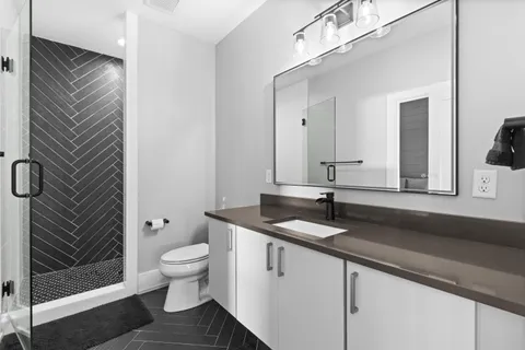 a bathroom with a granite countertop sink a toilet and a mirror