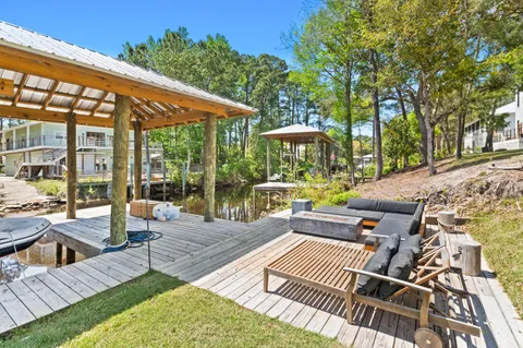 a view of a patio with couches table and chairs and potted plants with large tree