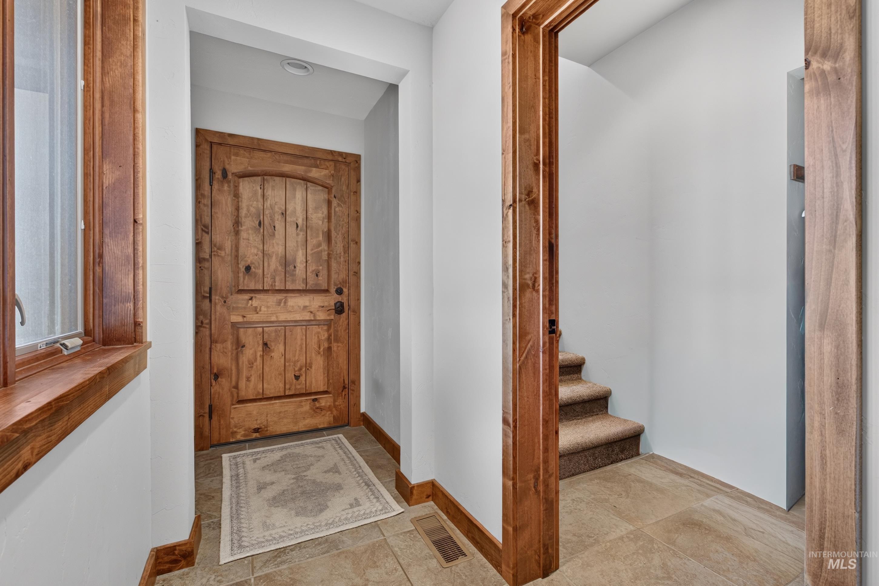 63 Mountain View Road Salmon, ID 83467 - Photo 39 of 50 Entryway featuring a solid wood panel door with an arched top, tile flooring, wood-framed window, recessed lighting, and wood trim