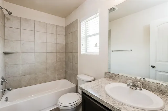 a bathroom with a granite countertop sink toilet a mirror and bathtub