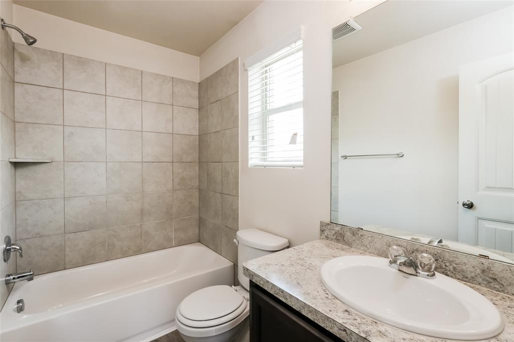 1605 Cardinal Drive Ennis, TX 75119 - Photo 12 of 16 a bathroom with a granite countertop sink toilet a mirror and bathtub