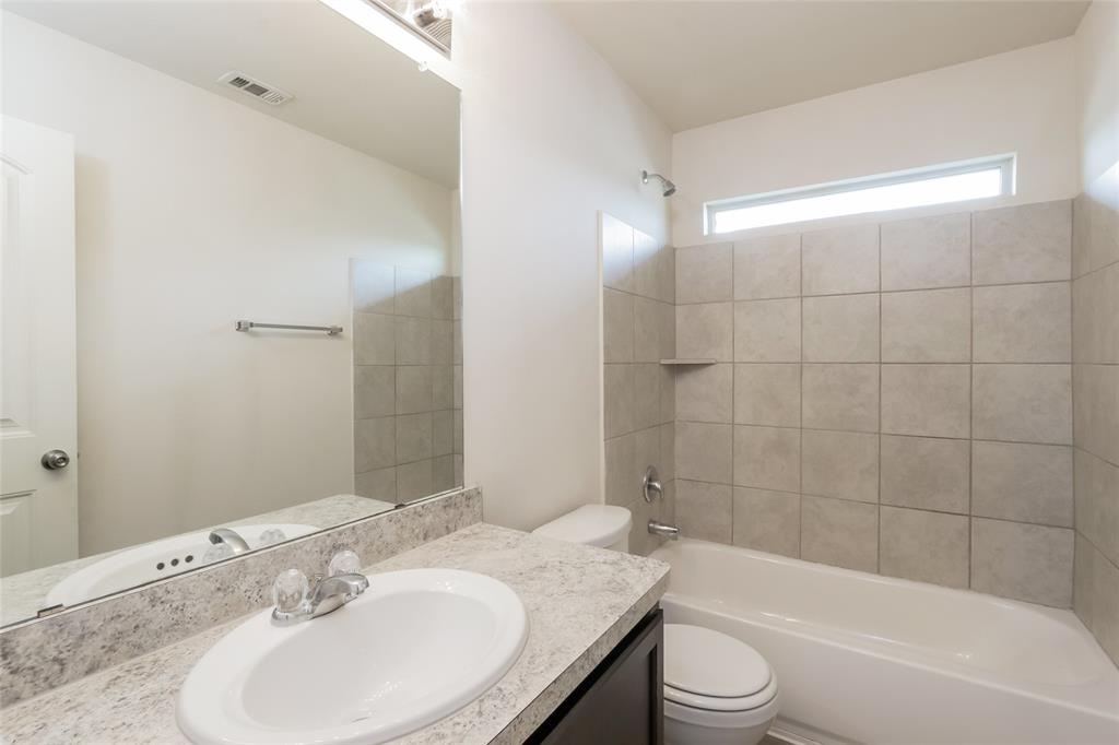 1605 Cardinal Drive Ennis, TX 75119 - Photo 7 of 16 a bathroom with a granite countertop sink a toilet a mirror and bathtub