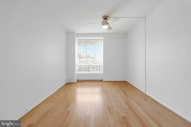 an empty room with wooden floor chandelier fan and windows
