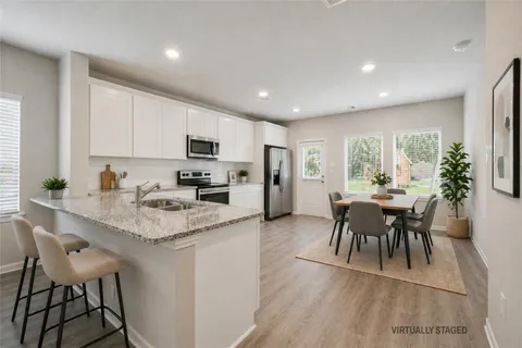 a kitchen with stainless steel appliances granite countertop a table chairs sink and cabinets