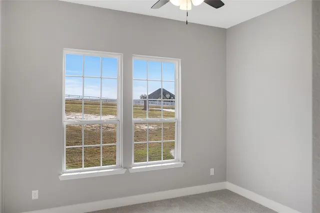 an empty room with windows and ceiling fan