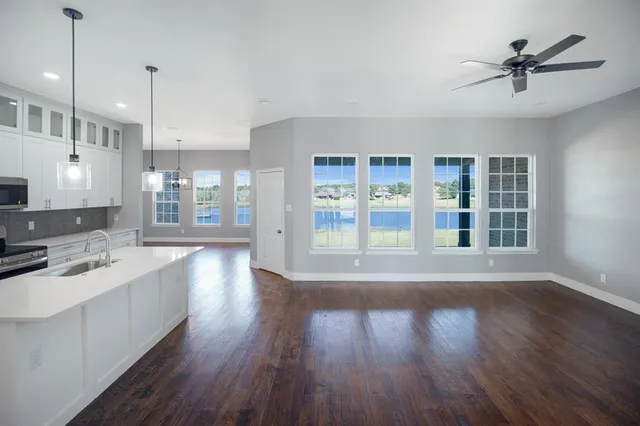 a kitchen with kitchen island granite countertop a stove top oven a sink and white cabinets
