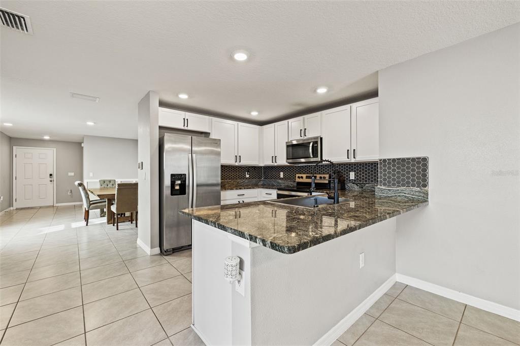 12115 Lily Magnolia Lane Riverview, FL 33569 - Photo 8 of 41 a kitchen with stainless steel appliances granite countertop a sink refrigerator and cabinets