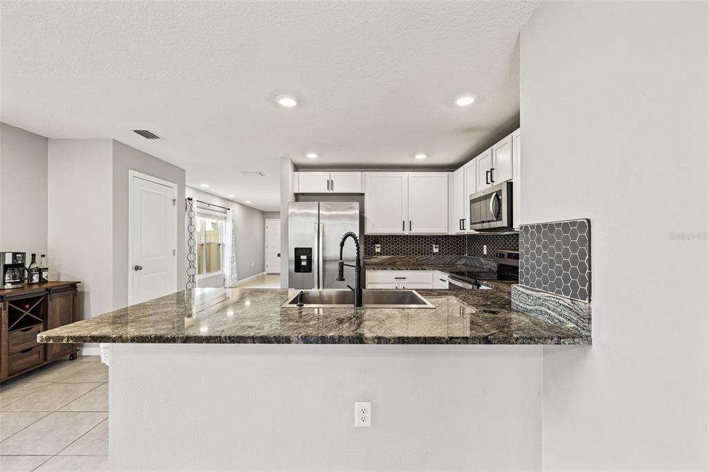 12115 Lily Magnolia Lane Riverview, FL 33569 - Photo 10 of 41 a kitchen with kitchen island granite countertop a sink and a counter top space