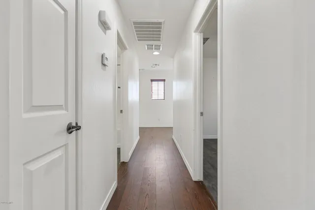 a view of a hallway with wooden floor and a bathroom