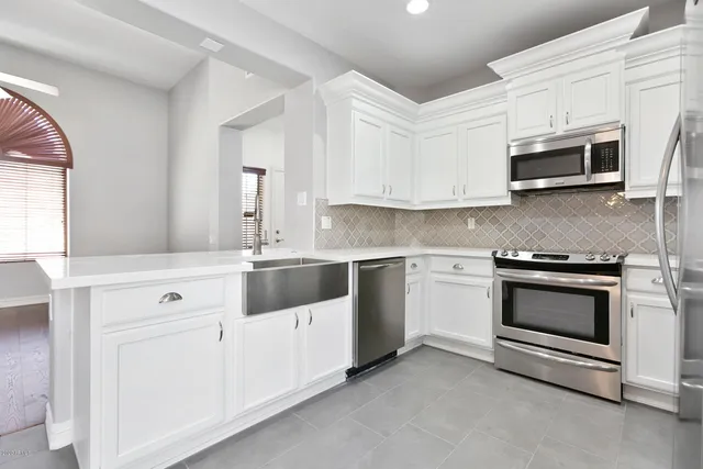 a kitchen with stainless steel appliances granite countertop grey cabinets a sink and a stove