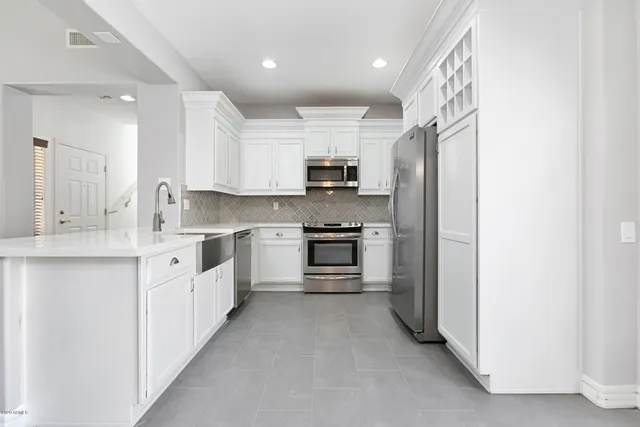 a kitchen with granite countertop white cabinets and stainless steel appliances