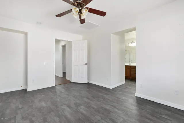 an empty room with wooden floor and a ceiling fan