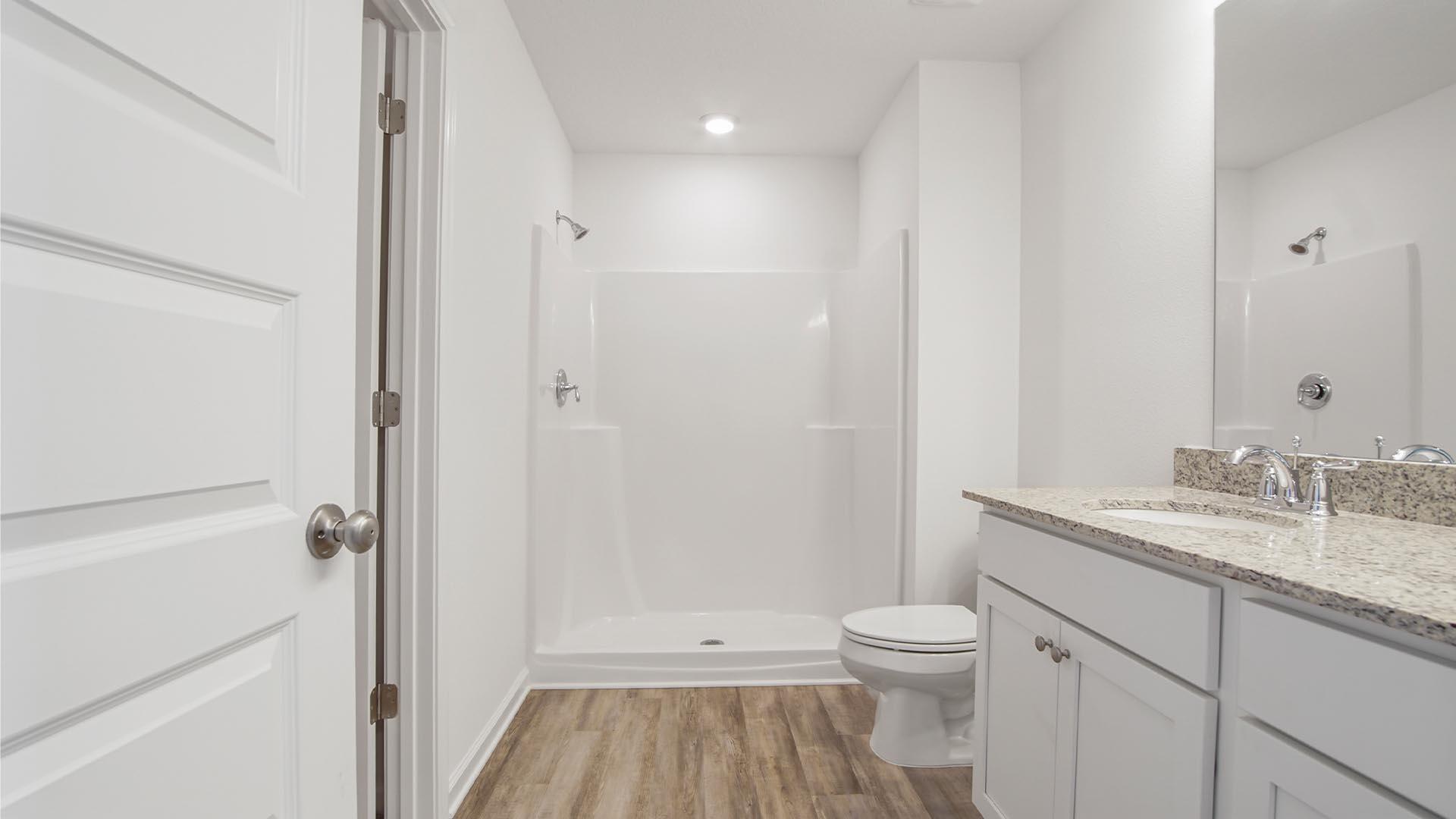 226 Huckleberry Street Freeport, FL 32439 - Photo 11 of 32 a bathroom with a granite countertop toilet a sink and a mirror