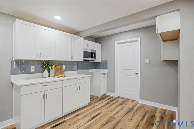 a kitchen with white cabinets and sink