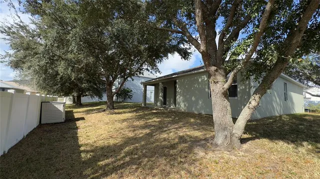 a view of a yard with wooden fence and a large tree
