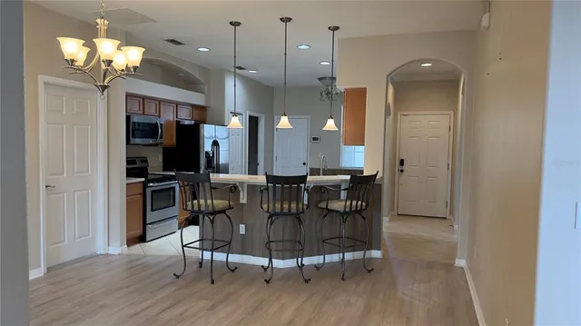 an empty room with a chandelier fan and wooden floor