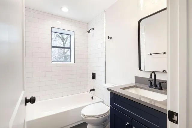a bathroom with a granite countertop sink a toilet and shower