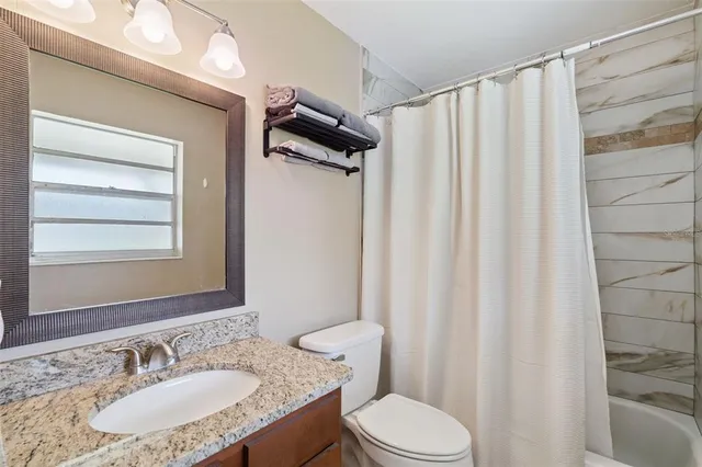a bathroom with a granite countertop sink toilet and mirror