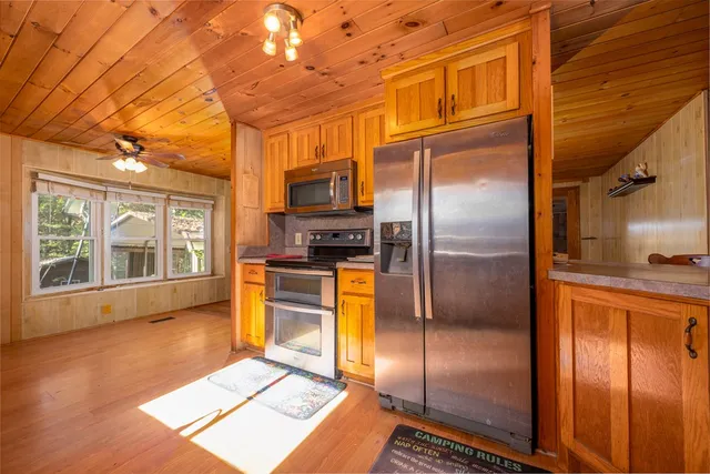 a kitchen with stainless steel appliances granite countertop a refrigerator a stove and a sink with wooden floor