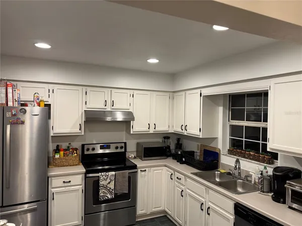a kitchen with granite countertop a refrigerator a sink dishwasher stove and oven