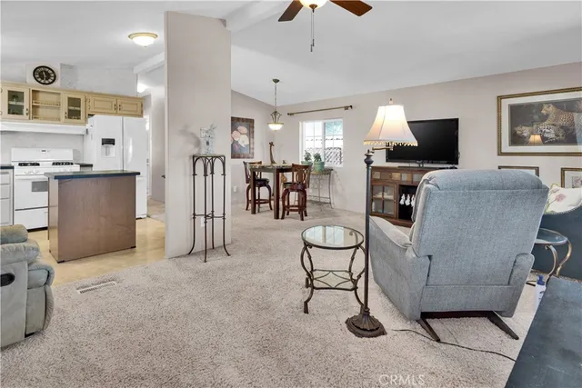 a living room with furniture a flat screen tv and kitchen view