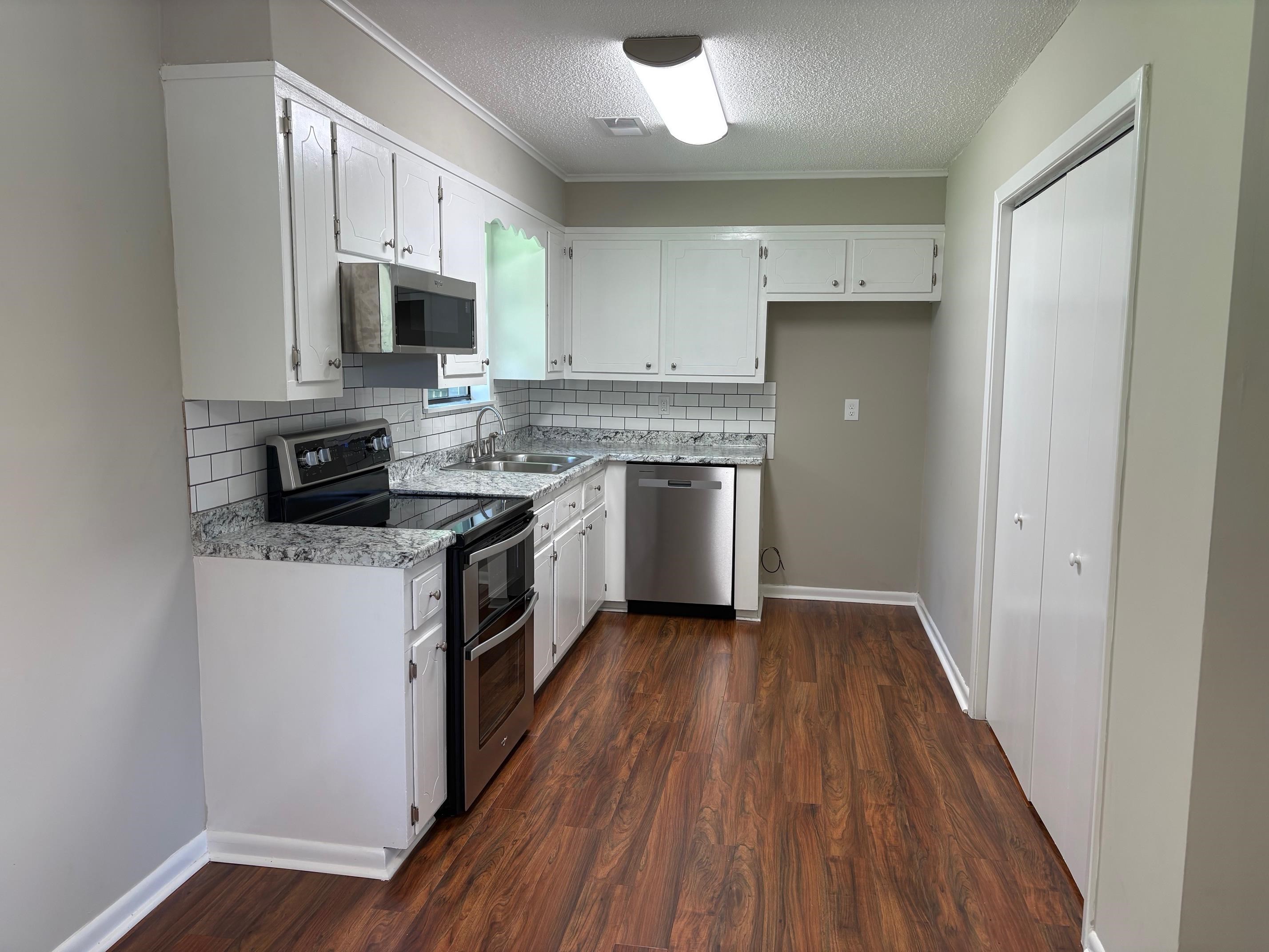 306 Robin Drive Ripley, TN 38063 - Photo 7 of 17 a kitchen with stainless steel appliances granite countertop a stove top oven a sink and a microwave