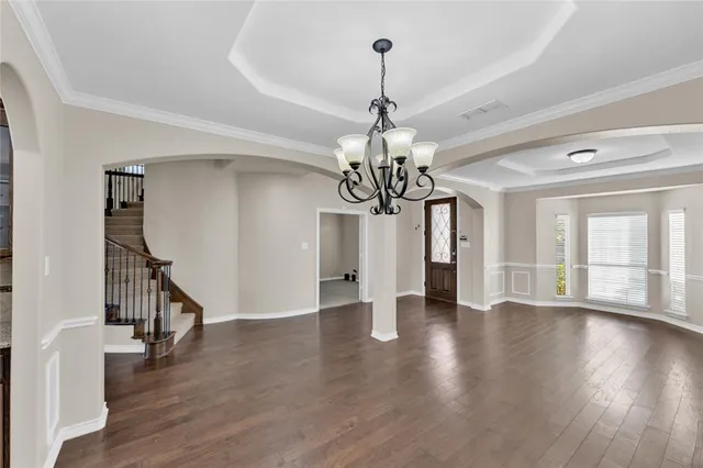 a view of a room with wooden floor chandelier and windows