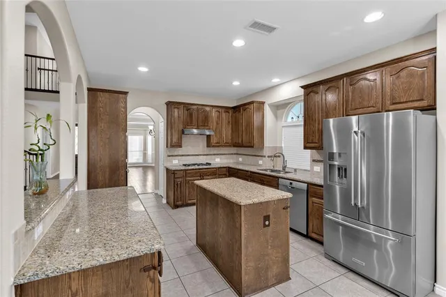 a kitchen with stainless steel appliances granite countertop a refrigerator a sink and a stove