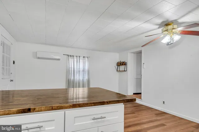 a kitchen with stainless steel appliances granite countertop a stove a sink and white cabinets with wooden floor next to windows