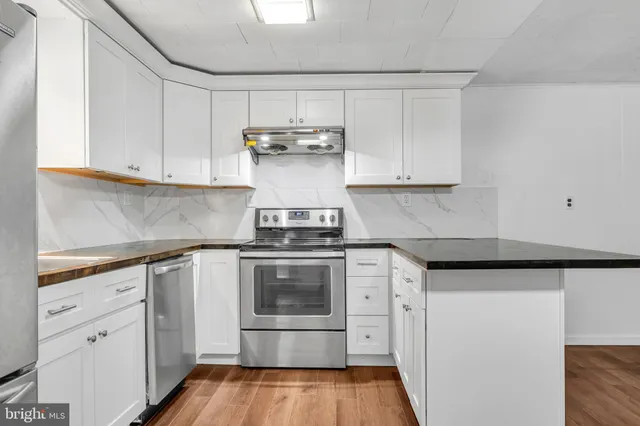 a kitchen with stainless steel appliances granite countertop a refrigerator sink and white cabinets