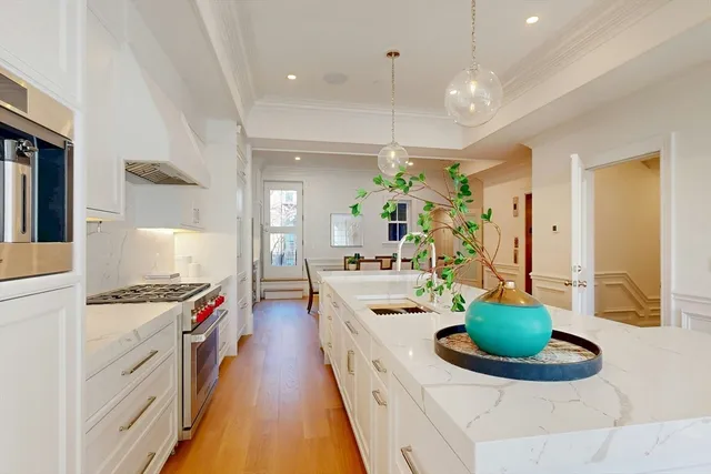 a large white kitchen with a stove and a view of living room