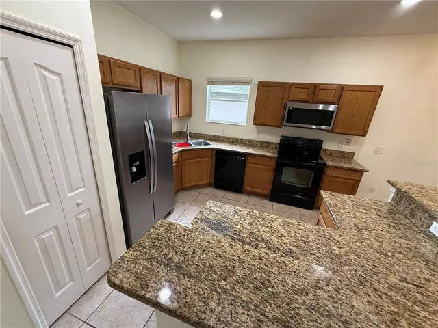 a kitchen with stainless steel appliances granite countertop a sink a stove and a refrigerator with wooden floor