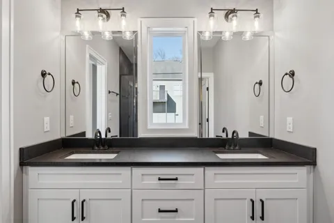 a bathroom with double sink and two mirror