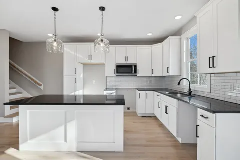 a kitchen with stainless steel appliances granite countertop a sink a stove and a refrigerator