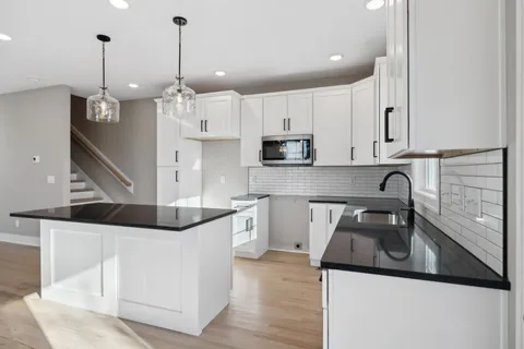 a kitchen with stainless steel appliances kitchen island granite countertop a sink a stove and a wooden floors