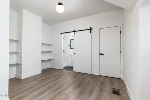 a view of empty room with wooden floor and window