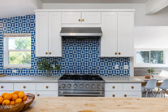 a kitchen with a sink a stove and white cabinets
